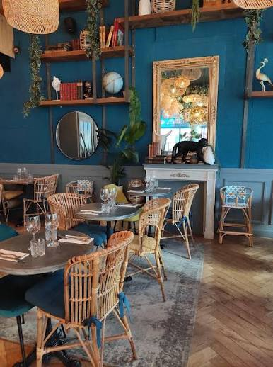 La salle bleue de Loulou Boulogne avec ses tables dressées et ses fauteuils en rotin